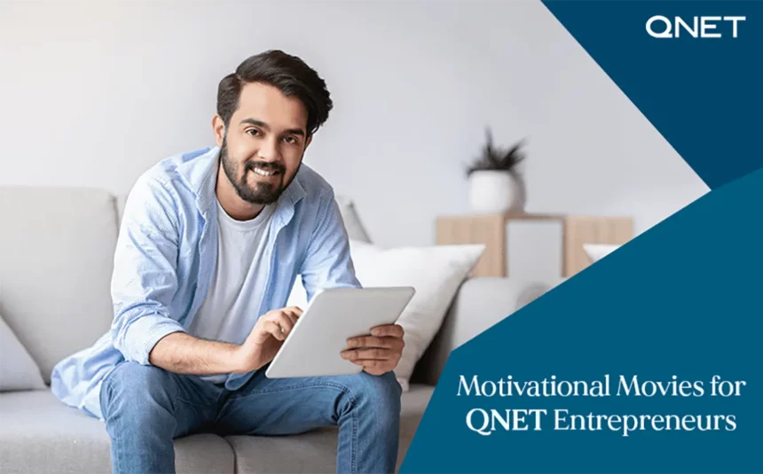 A young QNET entrepreneur smiling while watching motivational movies on his tablet in an indoor setting