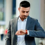 A young man looking at his wrist watch for time